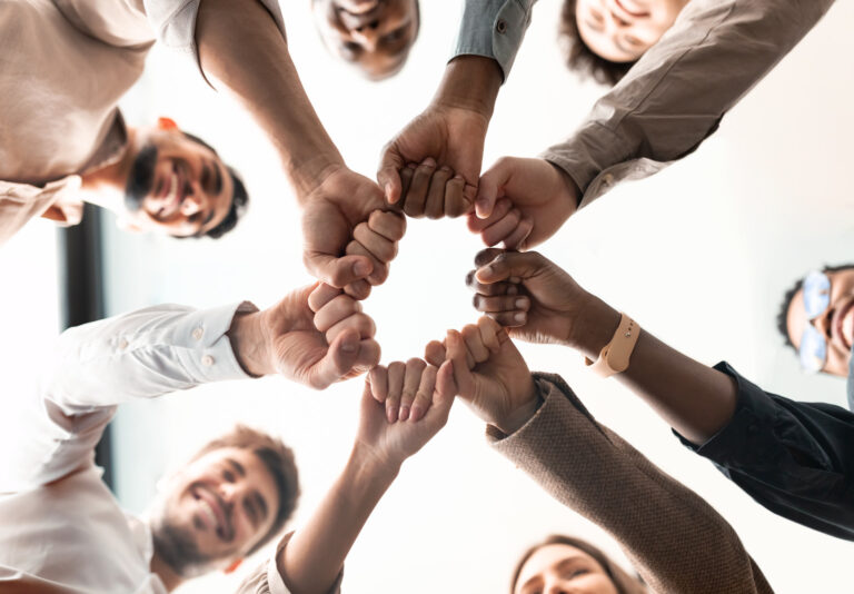 Team fist bump in a circle showing commitment to a culture transformation